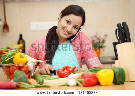 stock-photo-smiling-young-woman-cutting-vegetables-and-talking-on-cellphone-181403234